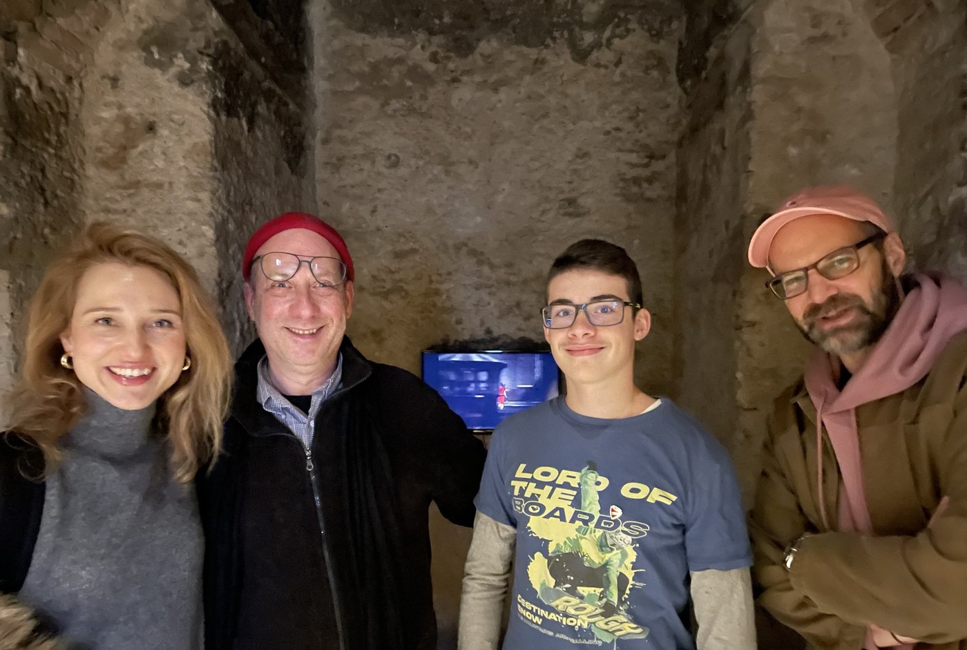 Four people standing together in a vaulted stone room at an exhibition