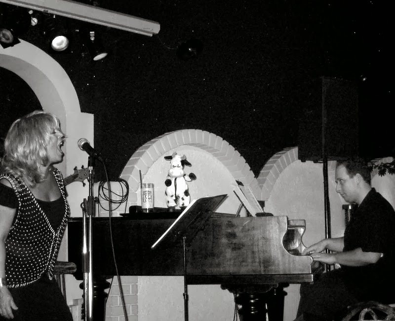 Magdi Bódy singing at the microphone with Grego at the grand piano in a club