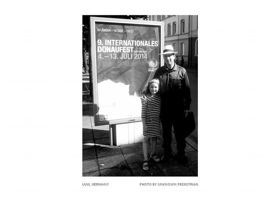 Grego and his daughter beside the 9th International Danube Festival poster in Ulm