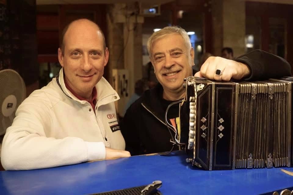 Grego and Fabio Turchetti at a table with a bandoneón beside them