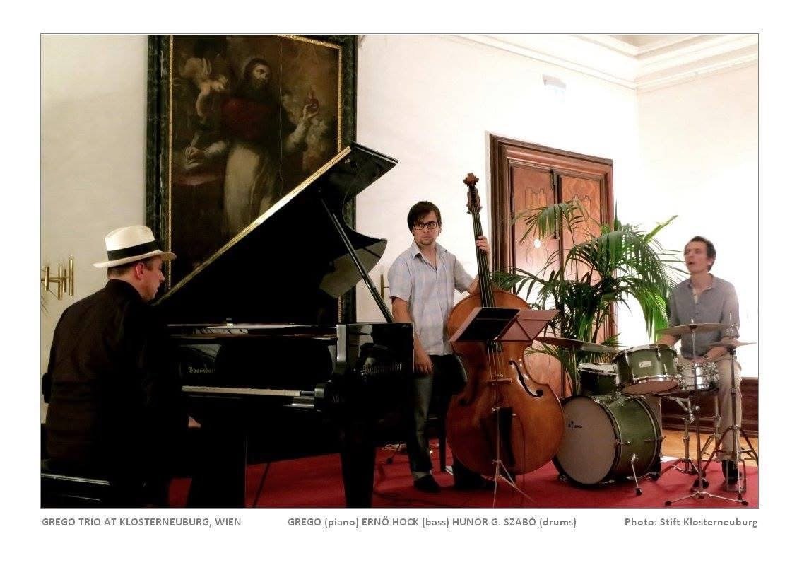 A piano trio playing in a baroque hall beneath a large altarpiece