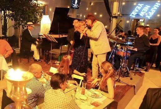 A band playing at a New Year’s Eve dinner, Grego at the grand piano, two singers at the microphone