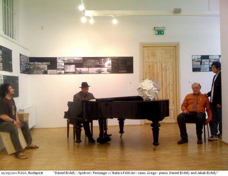 Grego at a grand piano with a white Spidron sculpture standing on it, listeners around the gallery