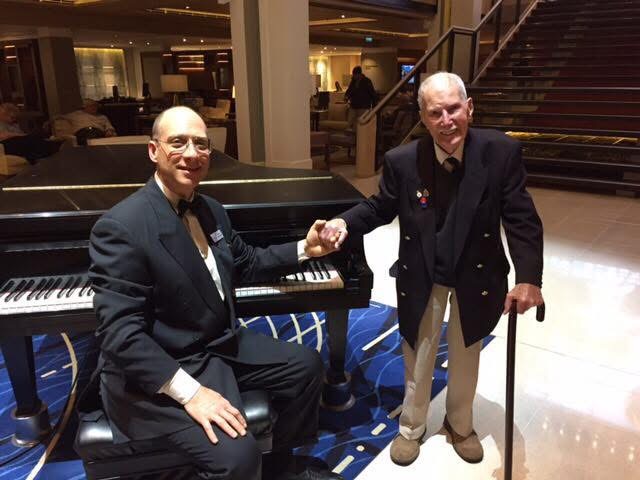 Grego at the piano shaking hands with a D-Day veteran aboard a Viking ship