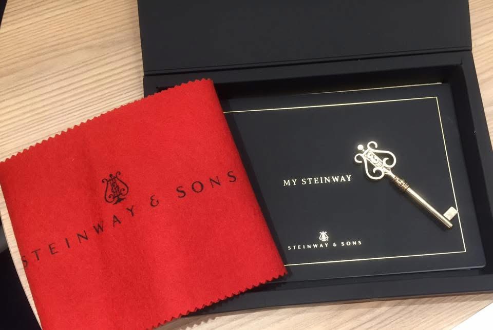 A Steinway and Sons presentation box holding a tuning key and a red cloth
